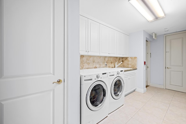 clothes washing area with cabinets, light tile patterned floors, washing machine and dryer, and sink