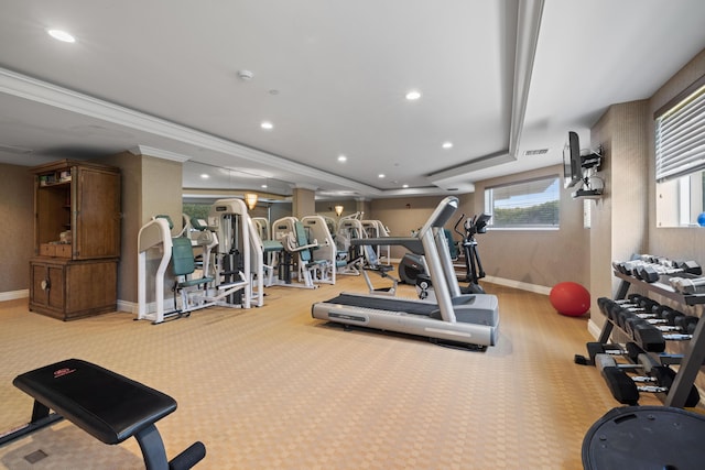 workout area featuring a raised ceiling, crown molding, and light colored carpet