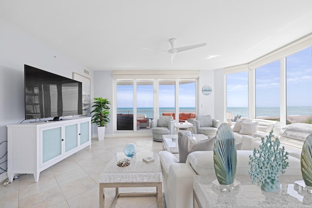 tiled living room featuring expansive windows, a water view, and ceiling fan