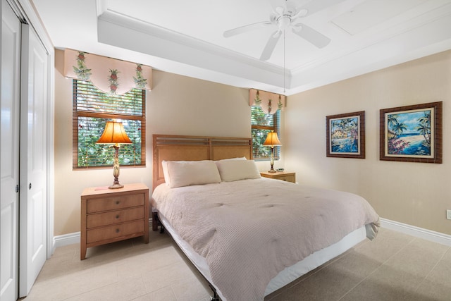 bedroom with ceiling fan, crown molding, a tray ceiling, and a closet