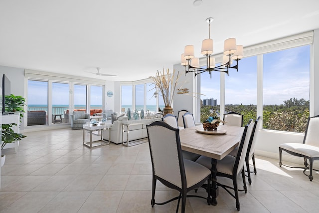 dining area featuring ceiling fan with notable chandelier, a water view, and light tile patterned flooring