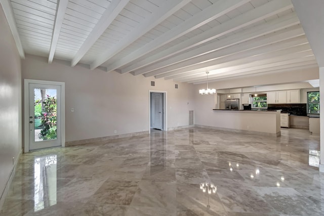 unfurnished living room with beam ceiling and a notable chandelier