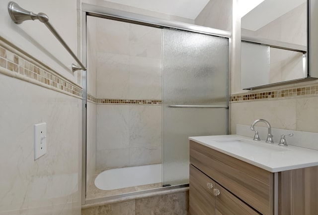 bathroom featuring enclosed tub / shower combo, vanity, and backsplash