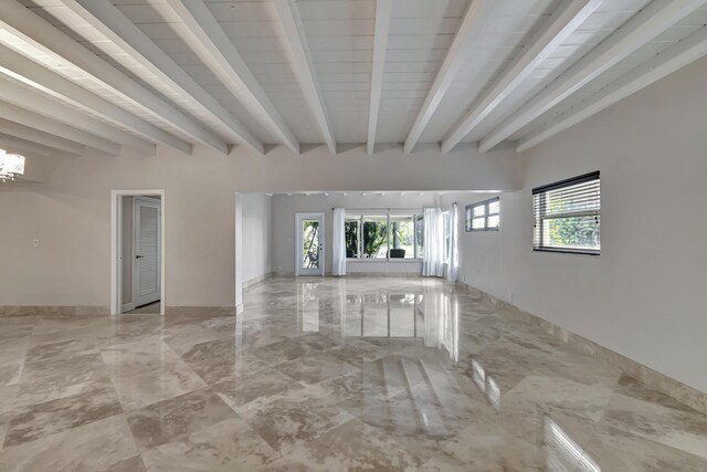 unfurnished living room featuring beamed ceiling and an inviting chandelier