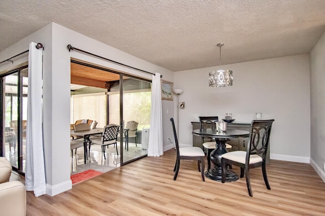 dining space with a notable chandelier, a textured ceiling, and light wood-type flooring