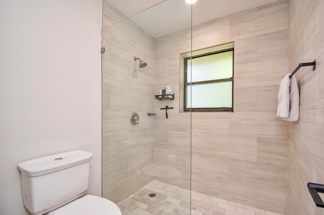 bathroom featuring toilet and a tile shower