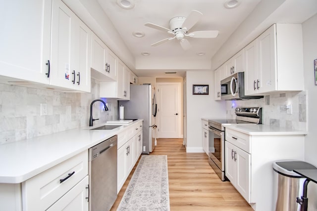 kitchen with appliances with stainless steel finishes, sink, white cabinets, and decorative backsplash