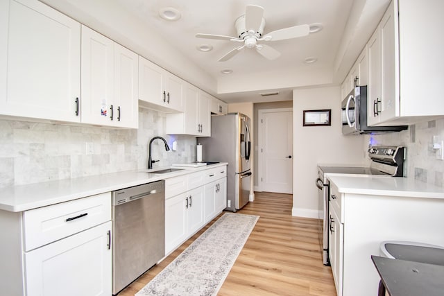 kitchen with white cabinetry, appliances with stainless steel finishes, tasteful backsplash, and light wood-type flooring