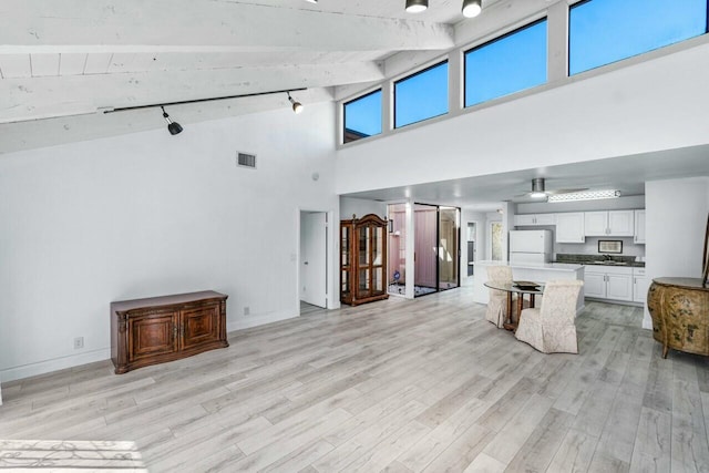 living room featuring sink, beamed ceiling, high vaulted ceiling, and light wood-type flooring