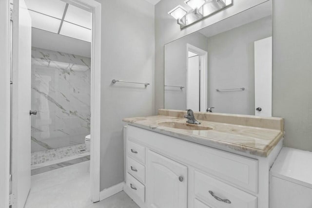 bathroom featuring toilet, vanity, and tiled shower