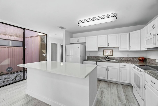 kitchen featuring white cabinetry, a center island, sink, white appliances, and light wood-type flooring