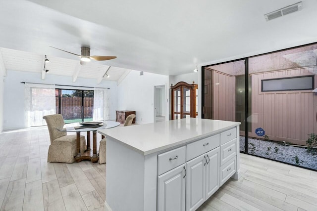 kitchen featuring a center island, white cabinets, vaulted ceiling with beams, ceiling fan, and light hardwood / wood-style floors