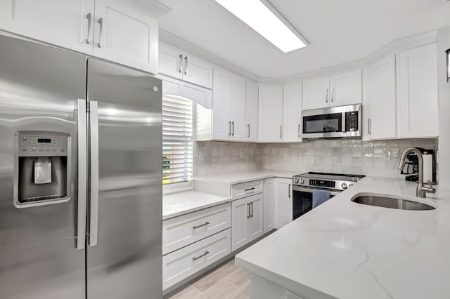 kitchen with stainless steel appliances, a sink, white cabinets, and decorative backsplash