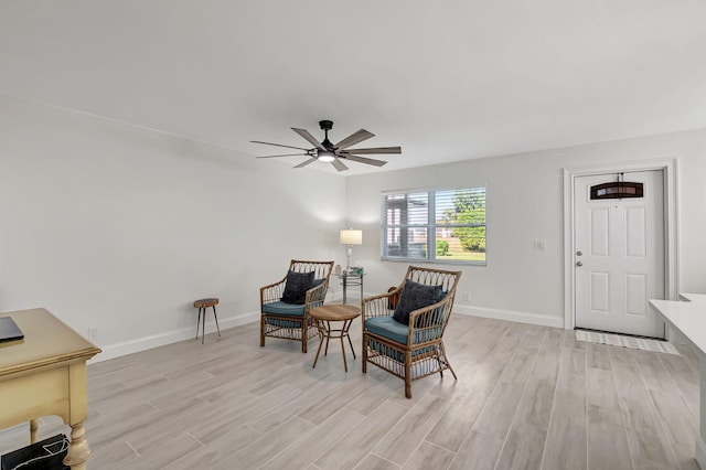 living area with light wood-type flooring, a ceiling fan, and baseboards