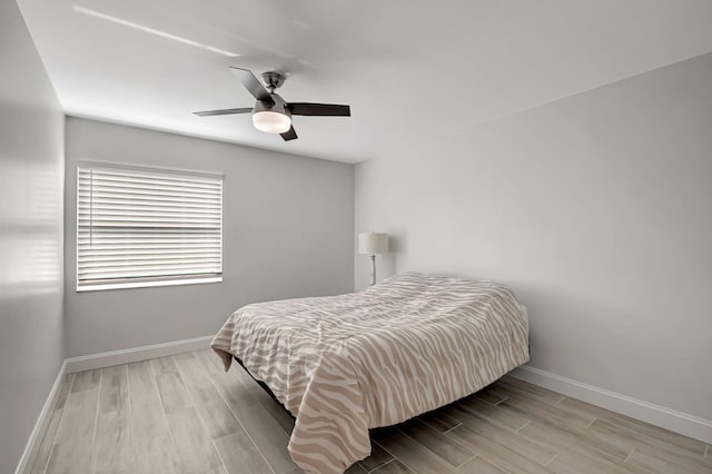 bedroom with a ceiling fan, baseboards, and wood finished floors