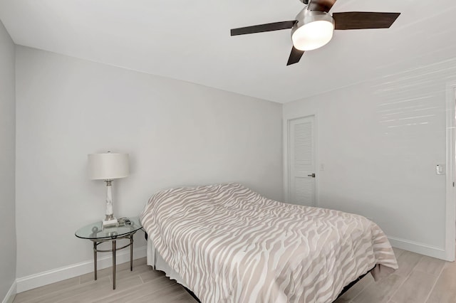 bedroom featuring wood tiled floor, a closet, baseboards, and a ceiling fan