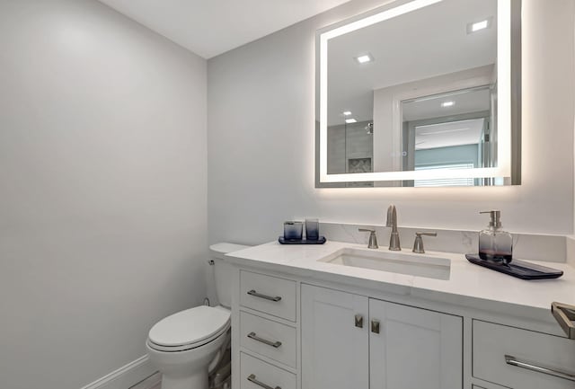 bathroom featuring a shower, vanity, toilet, and baseboards