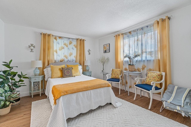 bedroom featuring a textured ceiling, baseboards, and wood finished floors