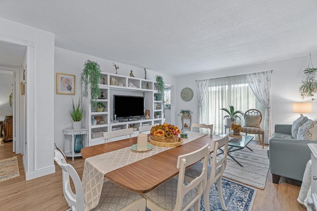 dining area with a textured ceiling and light hardwood / wood-style flooring