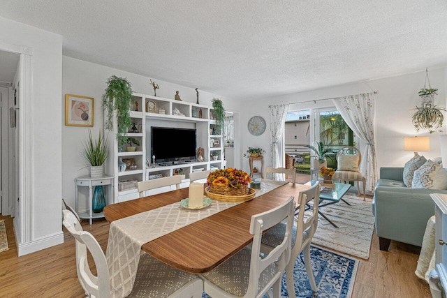 dining area with light wood-type flooring and a textured ceiling