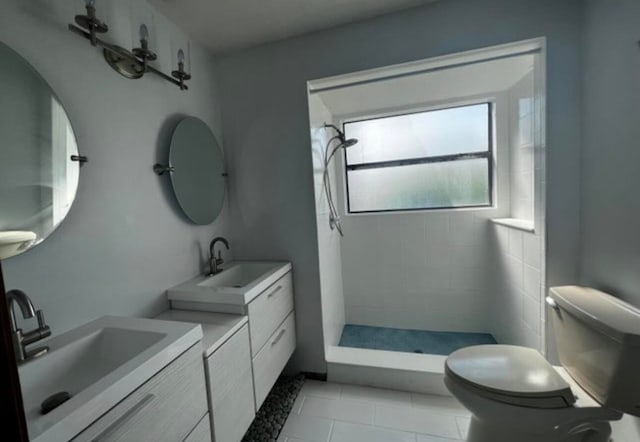 bathroom featuring toilet, a tile shower, tile patterned flooring, and double sink vanity