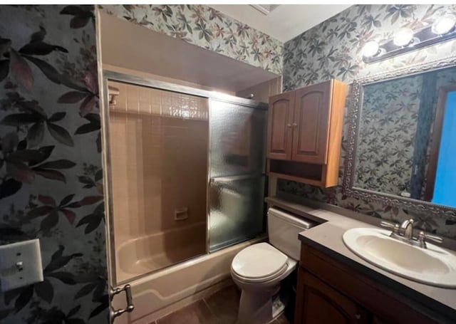 full bathroom with tile patterned floors, vanity, bath / shower combo with glass door, and toilet