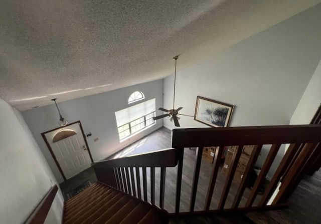 staircase featuring high vaulted ceiling, dark hardwood / wood-style flooring, a textured ceiling, and ceiling fan