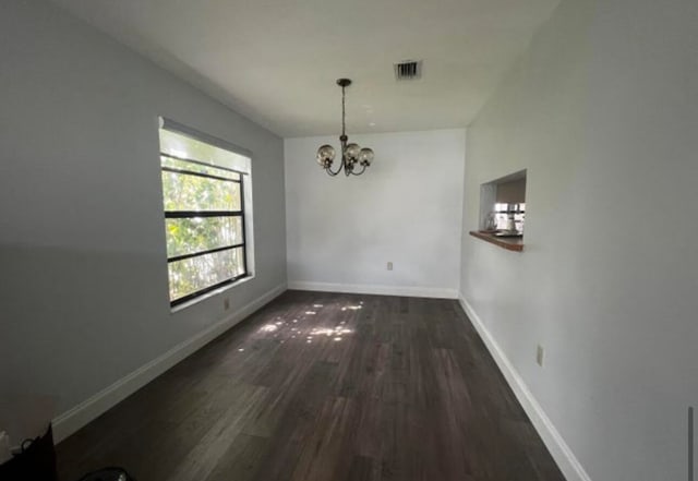 unfurnished dining area featuring dark hardwood / wood-style floors and a chandelier