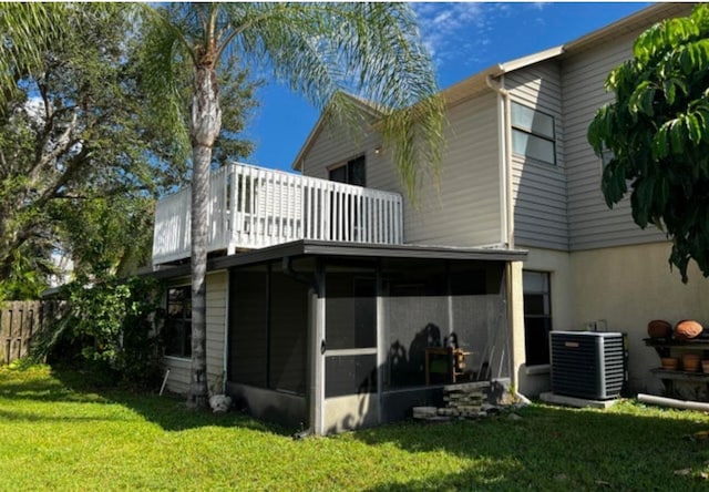 back of property featuring a sunroom, a lawn, and central AC unit