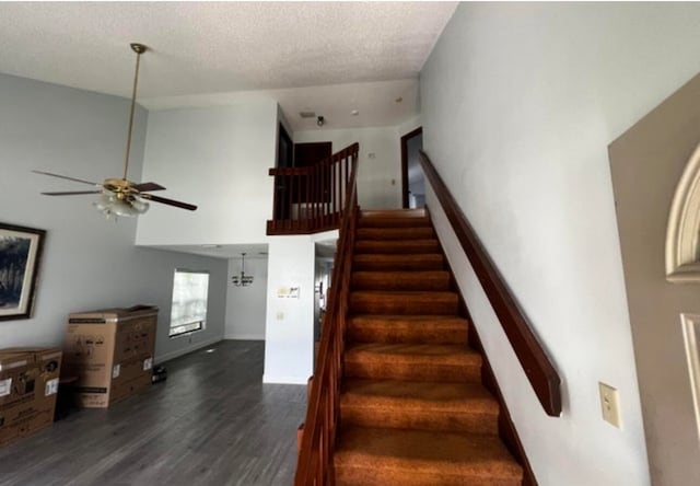 staircase with dark hardwood / wood-style flooring, a textured ceiling, ceiling fan, and a towering ceiling