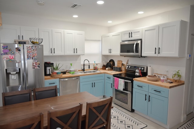 kitchen with wood counters, backsplash, sink, and stainless steel appliances