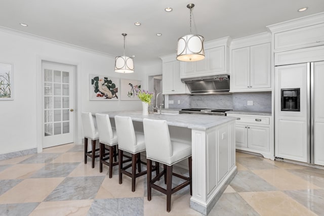 kitchen featuring an island with sink, a sink, crown molding, decorative backsplash, and extractor fan