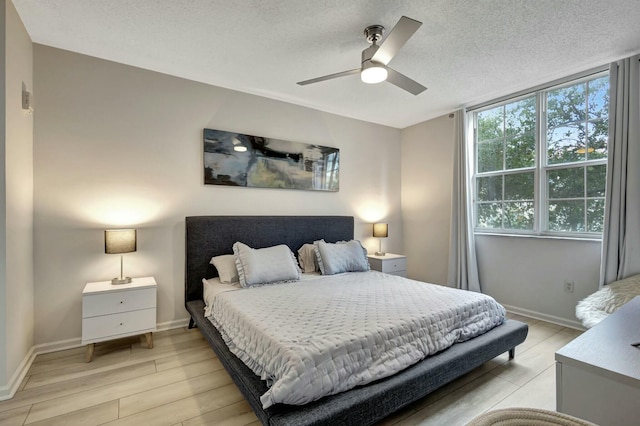 bedroom with ceiling fan, a textured ceiling, and light hardwood / wood-style flooring