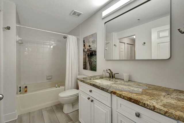 full bathroom with hardwood / wood-style floors, vanity, shower / tub combo, and toilet