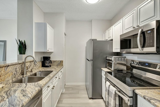 630 S Sapodilla Ave Unit 223, West Palm Beach, FL 33401 - kitchen featuring stainless steel appliances, a sink, a textured ceiling, white cabinets, and light stone counters