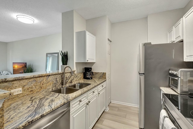 kitchen featuring white cabinetry, sink, light stone counters, and light hardwood / wood-style flooring