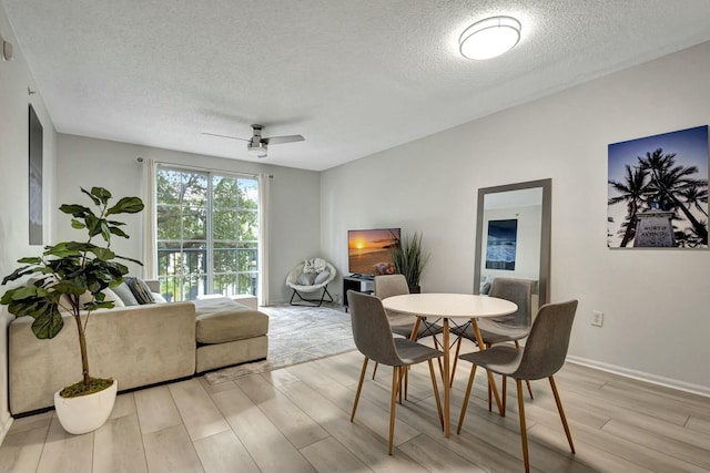 dining area featuring ceiling fan, a textured ceiling, and light wood-type flooring