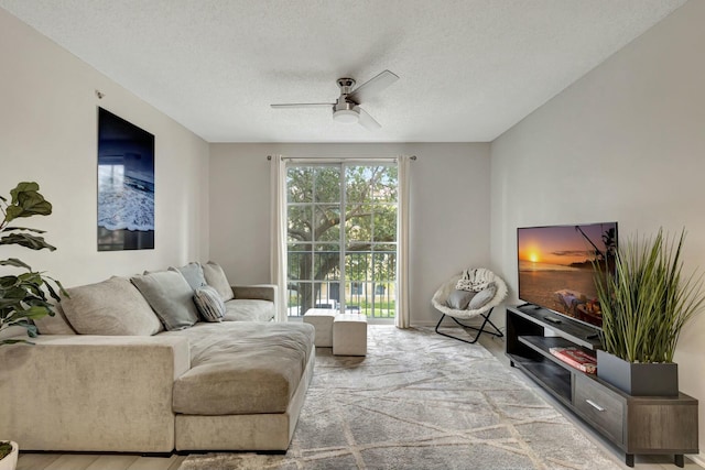 living room featuring ceiling fan and a textured ceiling