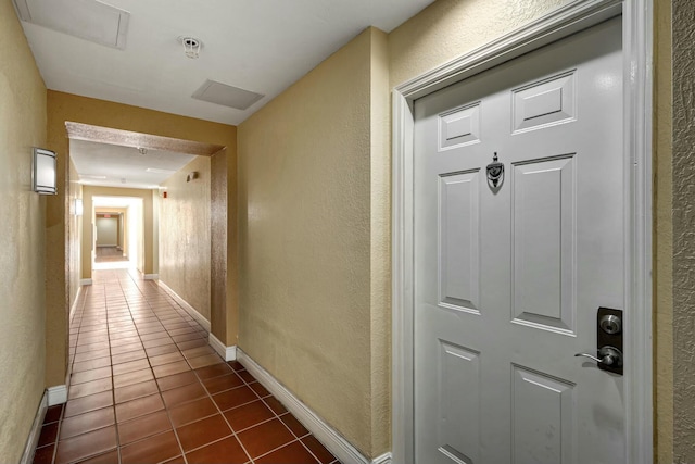 630 S Sapodilla Ave Unit 223, West Palm Beach, FL 33401 - hallway with dark tile patterned floors, a textured wall, and baseboards