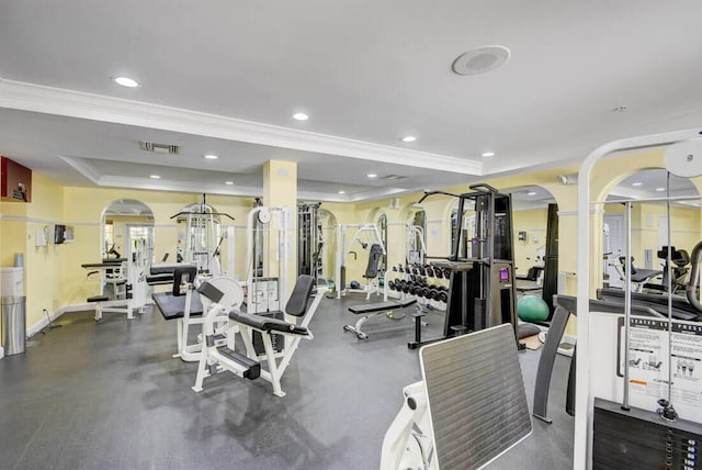 exercise room with a raised ceiling and crown molding