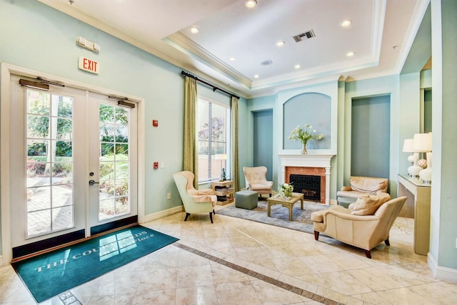 living area with a premium fireplace, ornamental molding, a raised ceiling, and french doors