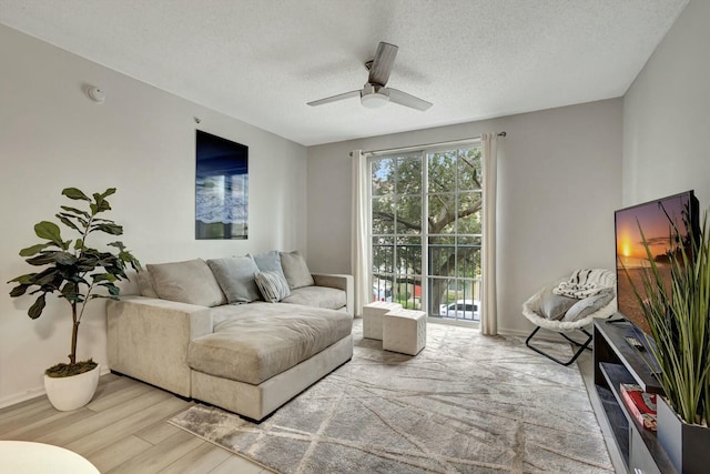 living room featuring ceiling fan, a textured ceiling, and light hardwood / wood-style flooring