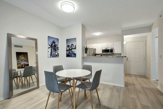 dining room with light hardwood / wood-style flooring and a textured ceiling