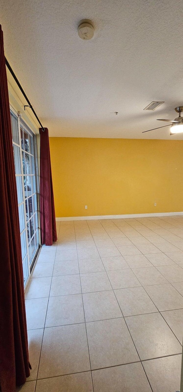 tiled empty room featuring ceiling fan and a textured ceiling