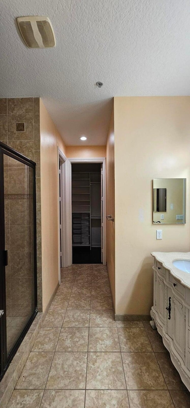 bathroom featuring tile patterned floors, a textured ceiling, an enclosed shower, and vanity