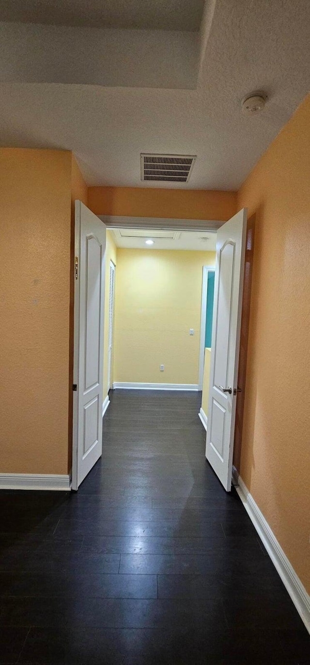 hallway with a textured ceiling and dark hardwood / wood-style floors