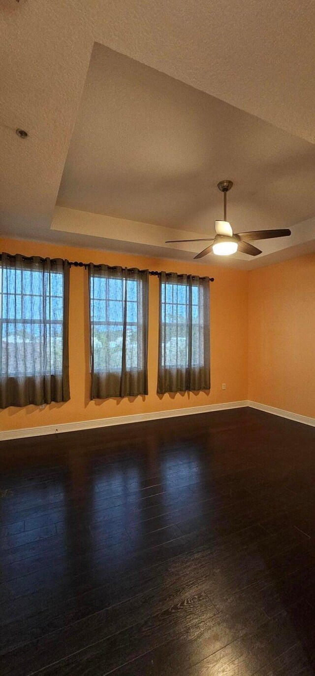 spare room with ceiling fan, a raised ceiling, and hardwood / wood-style floors