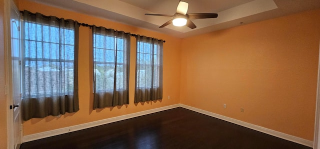 unfurnished room featuring ceiling fan, hardwood / wood-style flooring, and a tray ceiling