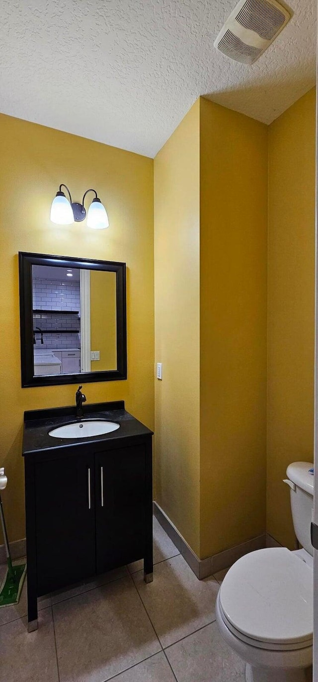 bathroom featuring a textured ceiling, toilet, vanity, and tile patterned flooring