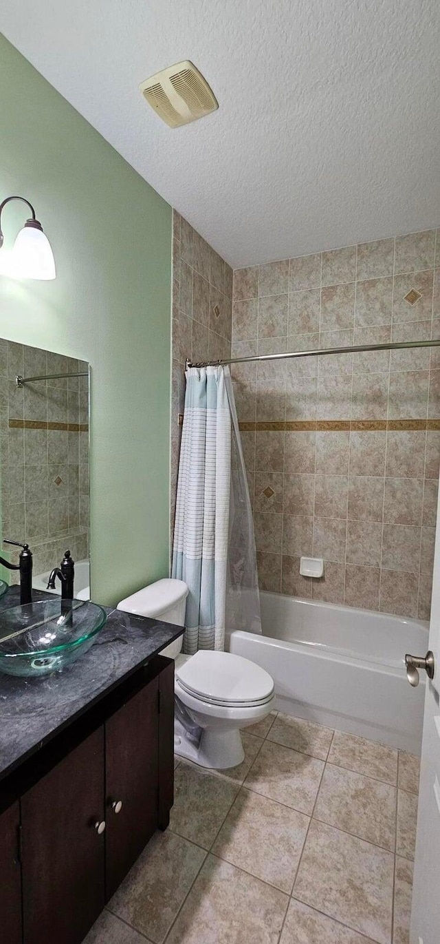 full bathroom featuring a textured ceiling, tile patterned flooring, vanity, toilet, and shower / bath combo